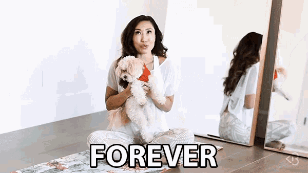 a woman is sitting on a yoga mat holding a dog and the word forever is on the floor in front of her