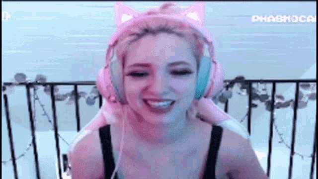a woman wearing pink cat ears and headphones is sitting in a chair .