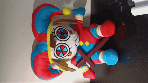 a stuffed clown is holding a cross in his right hand