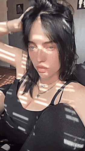 billie eilish is wearing a black top and a necklace