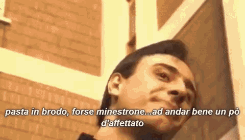 a man is standing in front of a brick wall and talking in a foreign language
