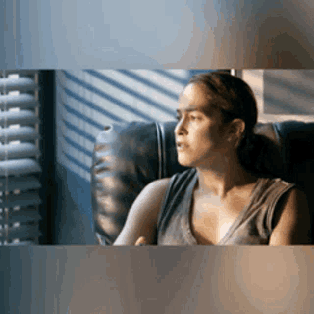 a woman is sitting in a chair and looking out a window