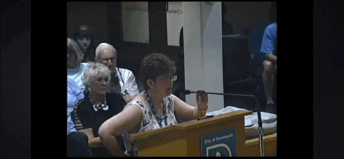 a woman stands at a podium with a sign that says city of boneport on it