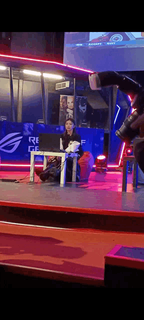 a woman sits at a table in front of a sign that says ' republic of gamers ' on it