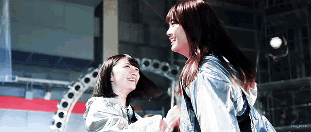 two women are standing next to each other and smiling while wearing metallic jackets