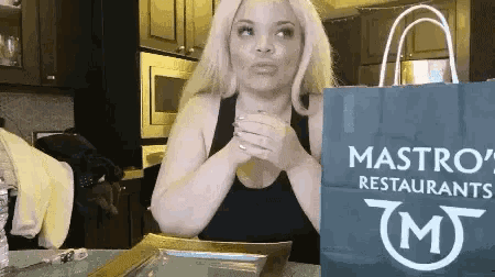 a woman is holding a blue bag that says mastro 's restaurants on it