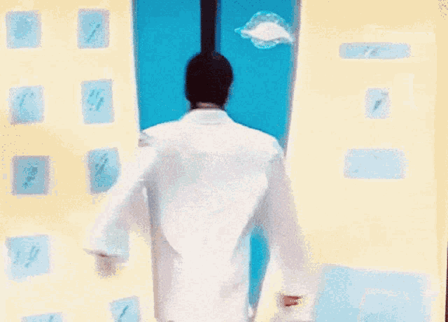 a man in a white coat is standing in front of a building with numbers on it