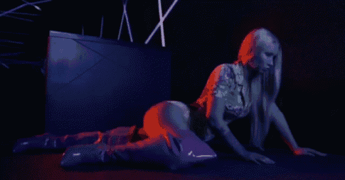 a woman with long blonde hair is kneeling on the floor in front of a sign that says xx