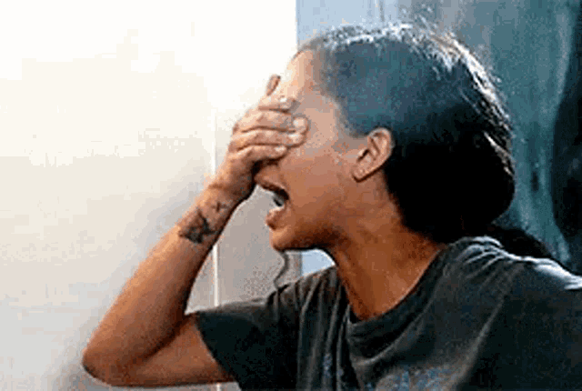 a woman is laughing while covering her face with her hand .