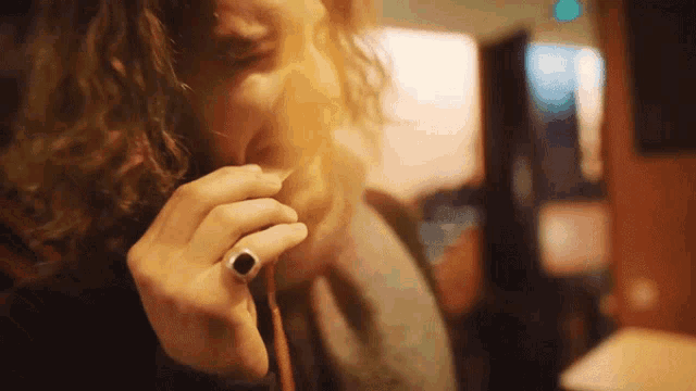 a woman with curly hair is wearing a black ring on her finger