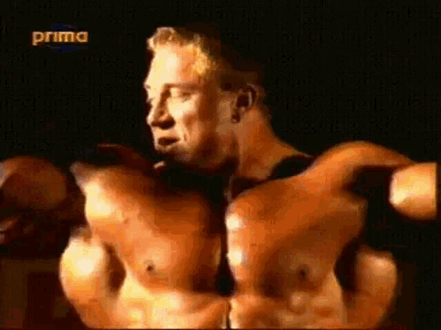 a very muscular man is flexing his muscles in front of a camera .