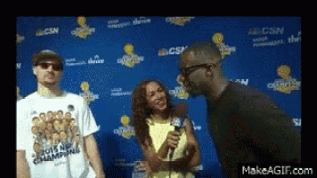 a man wearing a 2015 nba champions shirt is talking to a woman holding a microphone