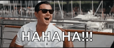 a man wearing sunglasses is laughing while sitting on a boat in front of boats .