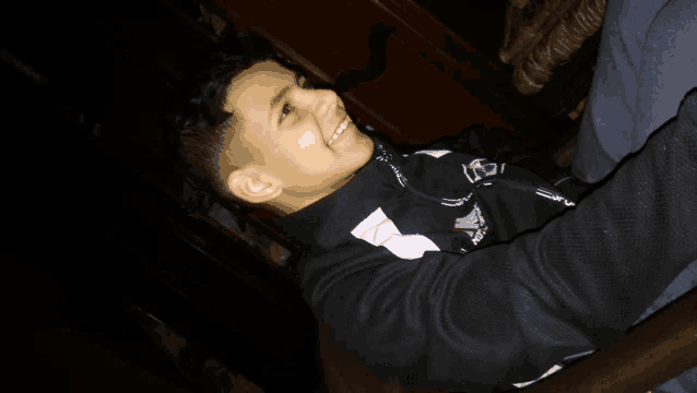 a young boy wearing a black and white jacket with the letter a on it smiles