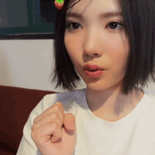 a woman wearing a white shirt has a strawberry hair clip on her head