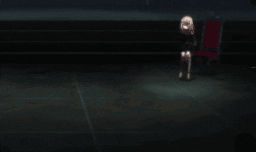 a person is kneeling down in a dark room with a red chair in the background