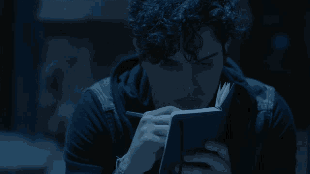 a man is writing in a notebook with a pen