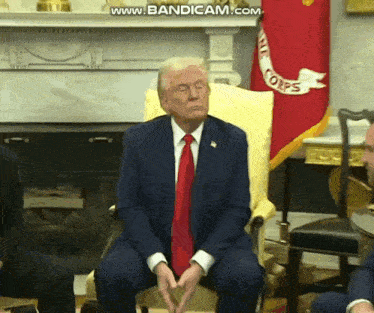 a man in a suit and tie is sitting in front of a flag that says corps