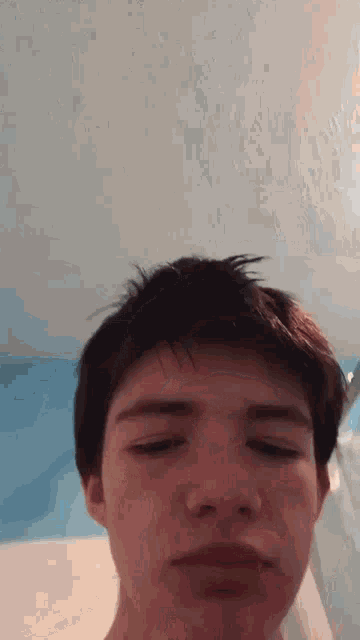 a young man is taking a selfie with his eyes closed in a bathroom .