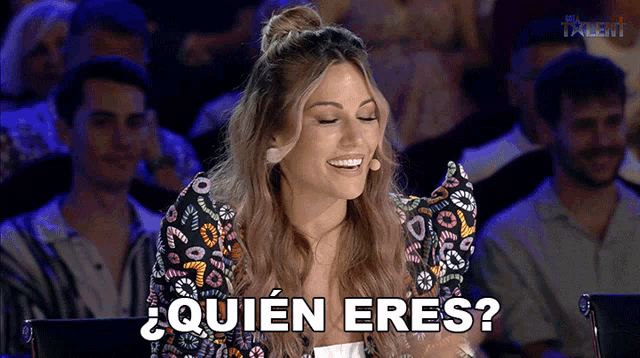 a woman sitting in front of a crowd with the words quien eres written on her face