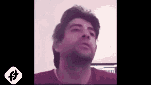 a man in a red shirt is making a funny face while looking at the camera .