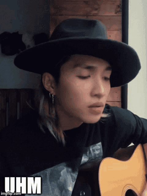 a young man wearing a black hat is playing a guitar with the hashtag iihm below him