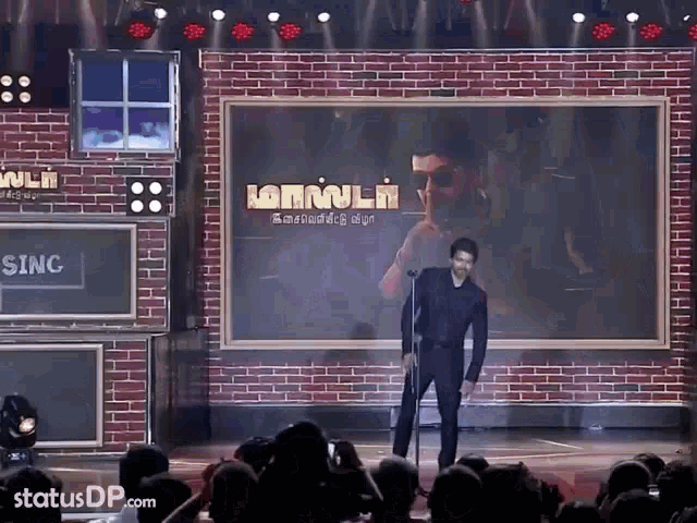 a man singing into a microphone in front of a brick wall that says sing on it