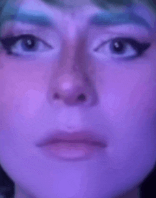 a close up of a woman 's face with purple lipstick and a purple background .