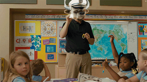 a man wearing a bull mask is standing in front of a classroom full of children