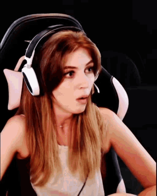 a woman wearing headphones is sitting in a chair and looking surprised