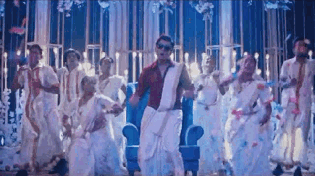 a man in a white saree is dancing with a group of people in white clothes .