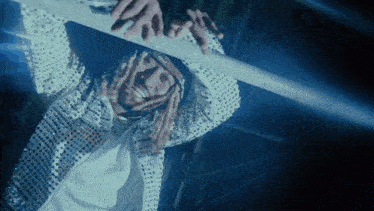 a man in a sequined jacket is reaching for a metal pole