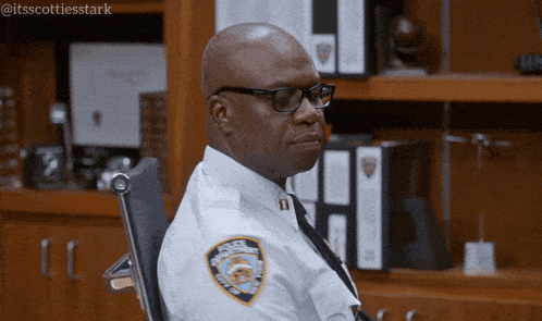 a man in a police uniform is sitting in a chair with a badge that says new york city police department