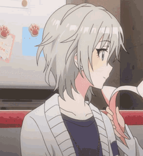 a girl in a white sweater is holding a pink object in her hand