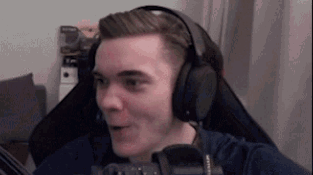 a man wearing headphones is sitting in front of a microphone and making a funny face .