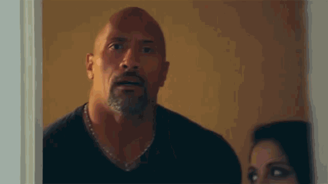 a man with a beard is standing in a doorway looking at a woman .