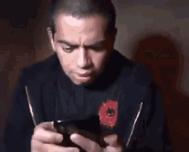 a man with a surprised look on his face is holding a cell phone in his hands .