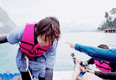 a person wearing a pink life vest is pointing at something