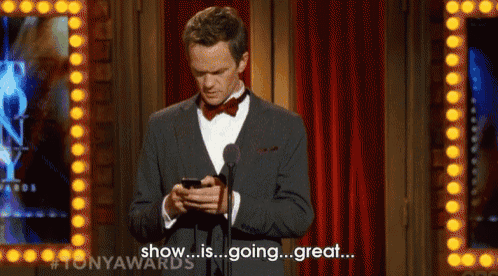 a man in a suit stands in front of a microphone and looks at his phone