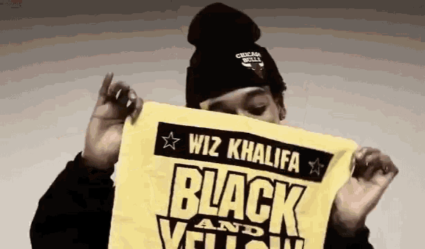wiz khalifa is holding a yellow towel that says black and yellow