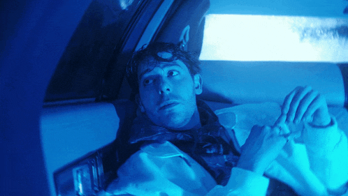 a man is laying in the back seat of a car with a blue light behind him