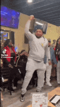 a man is dancing in front of a group of people in a restaurant while holding a bag over his head .