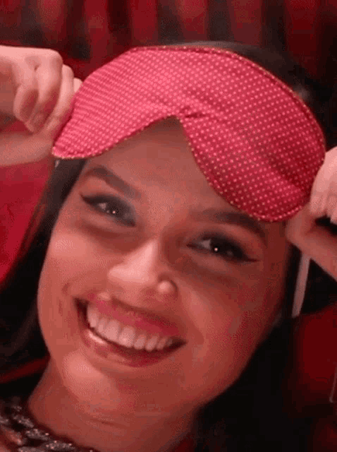 a woman wearing a red sleep mask is smiling