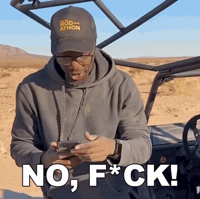 a man wearing a hat that says mod athlon looks at his phone