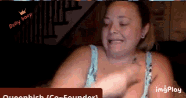 a woman with a tattoo on her chest is sitting in front of a sign that says imgplay