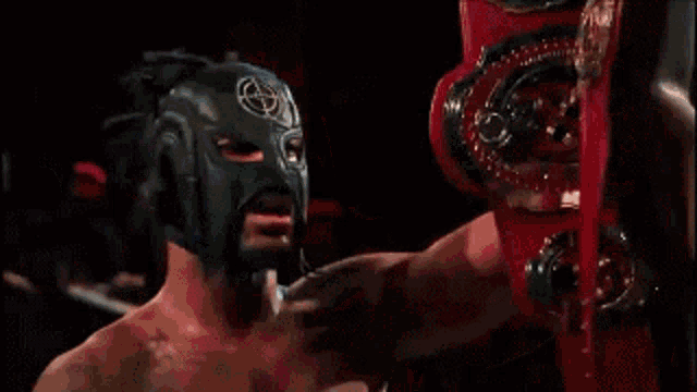 a man wearing a mask holds a red belt