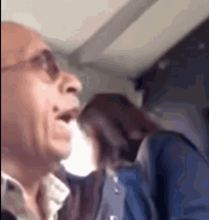 a man wearing sunglasses is talking to a woman on a plane .