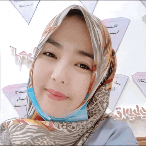 a woman wearing a scarf and a face mask smiles for a picture