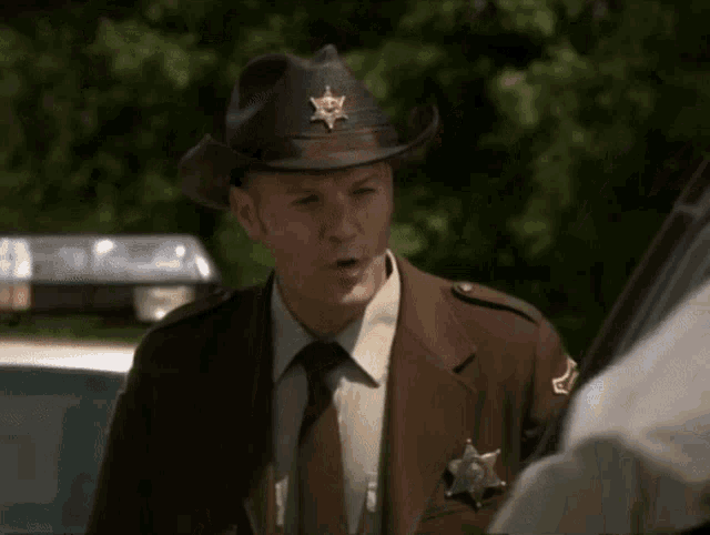 a man in a sheriff 's uniform with a cowboy hat