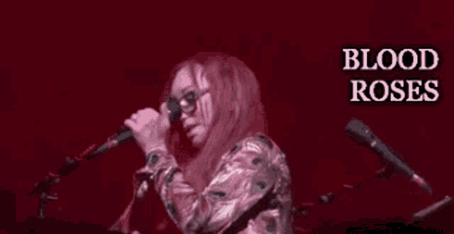 a woman singing into a microphone with the words blood roses written above her